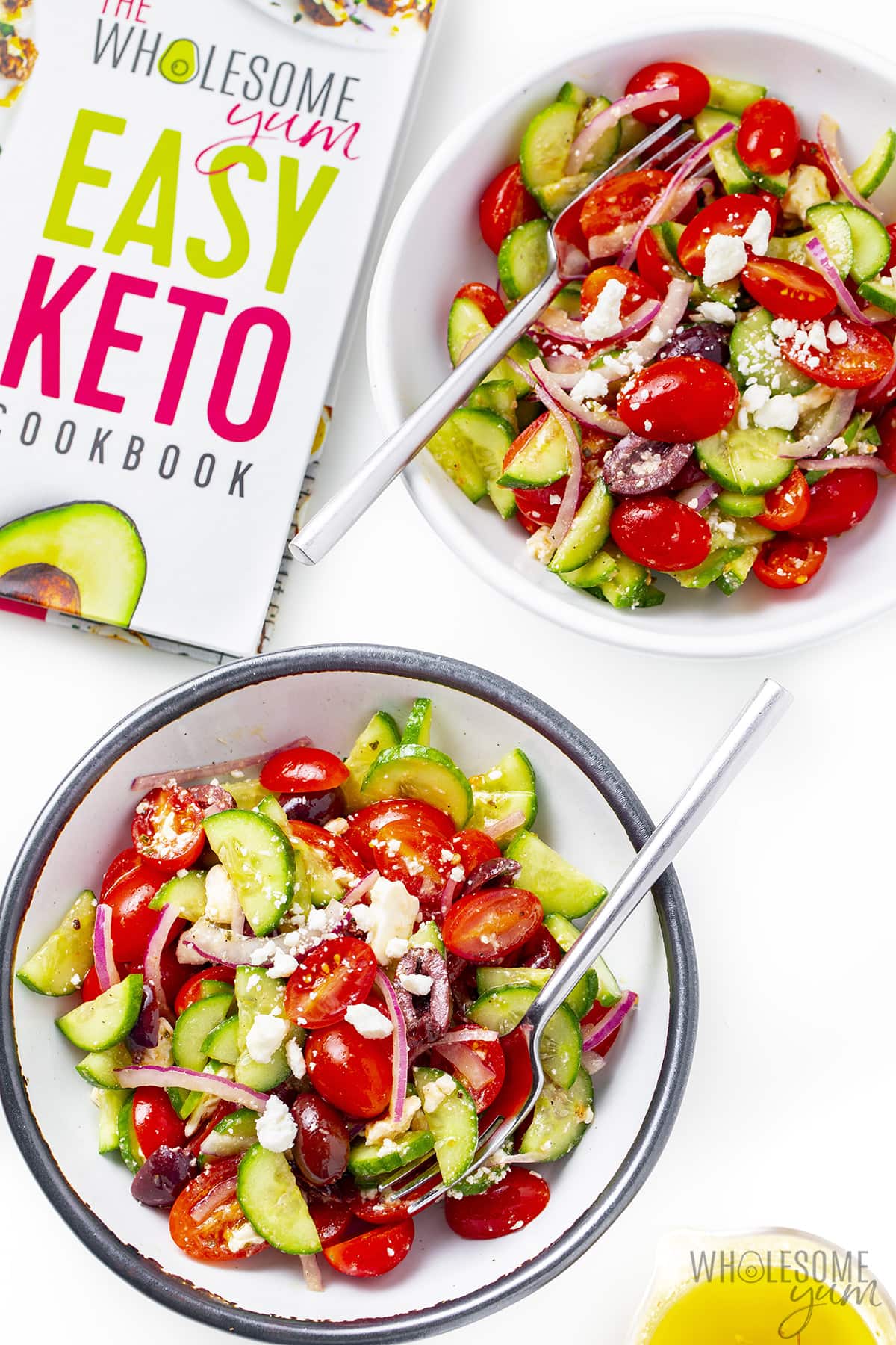 Greek salad recipe in two bowls next to cookbook.