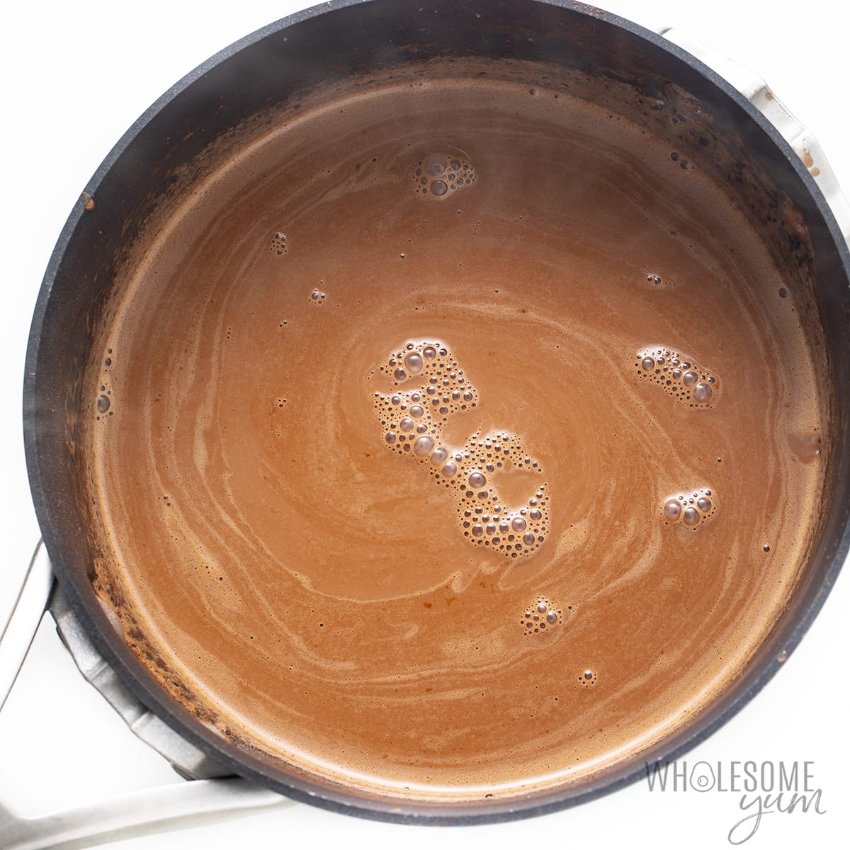 Whisked almond milk, cream, cocoa powder, and collagen simmering in saucepan. 