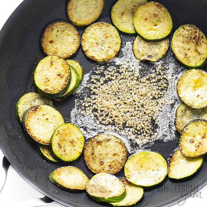 Push sautéed zucchini to the side of the pan with butter and garlic
