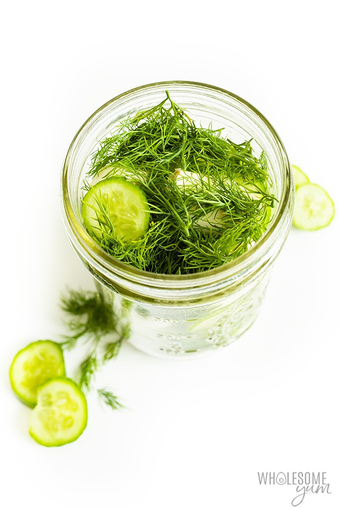 Side view of a jar of cucumbers with dill and garlic