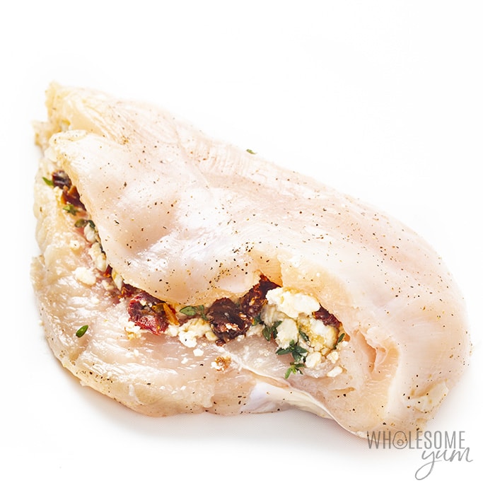 Chicken breast being stuffed for chicken with prosciutto and cheese