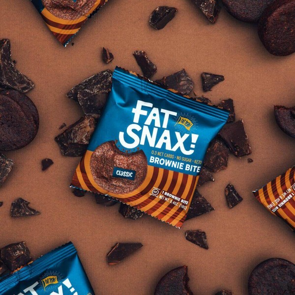Unopened Fat Snax brownie bite on top of pieces of chocolate