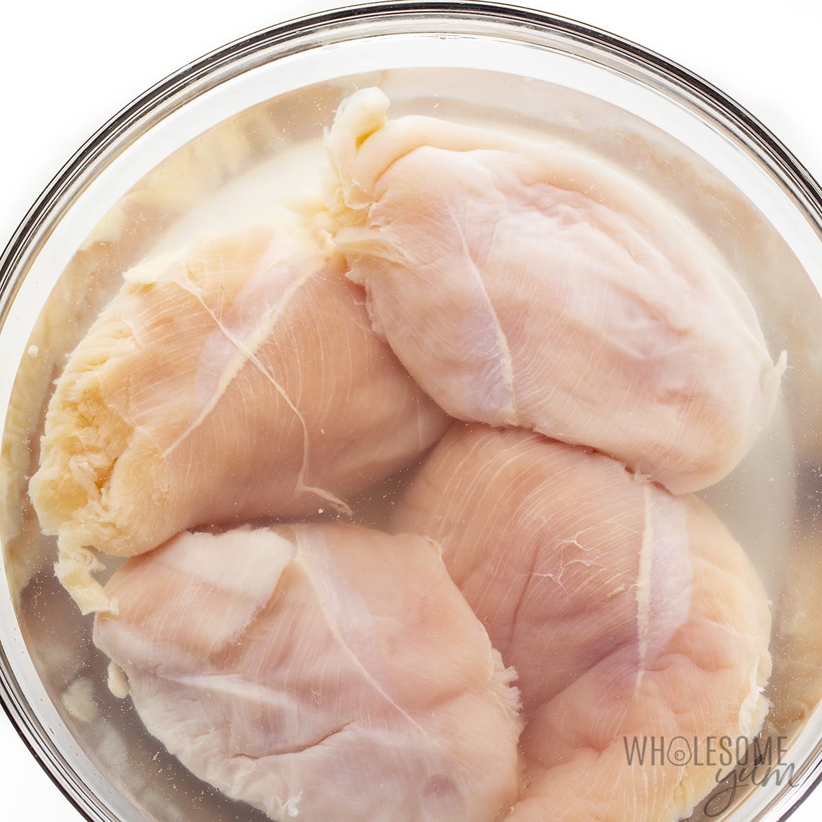 Chicken breast brining in a bowl.