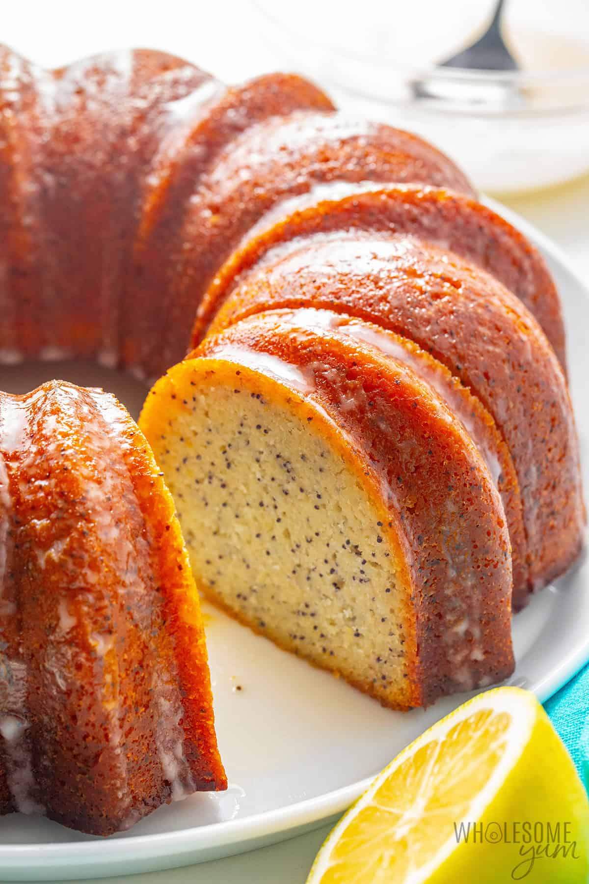 Moist, tender lemon bundt cake on a platter with a slice cut.