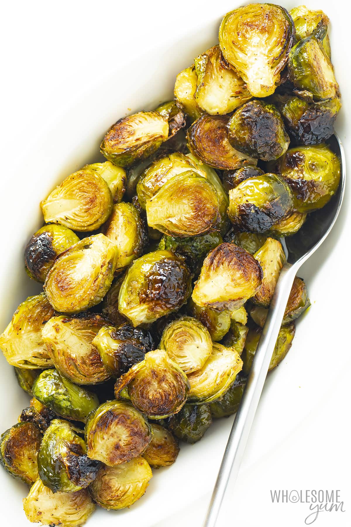 Brussels sprouts recipe on a white plate with a spoon.