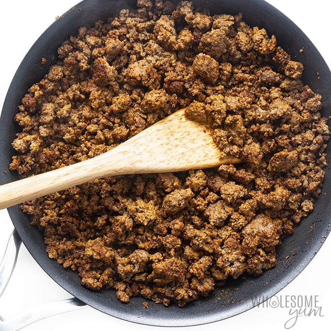 Overhead view of taco meat in a pan with a wooden spatula