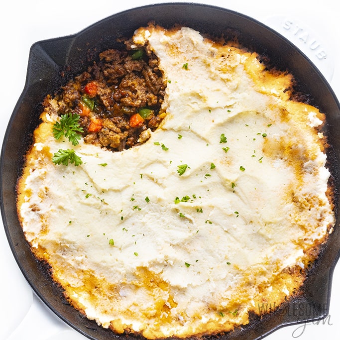 Baked cauliflower shepherd's pie in a skillet with the inside showing