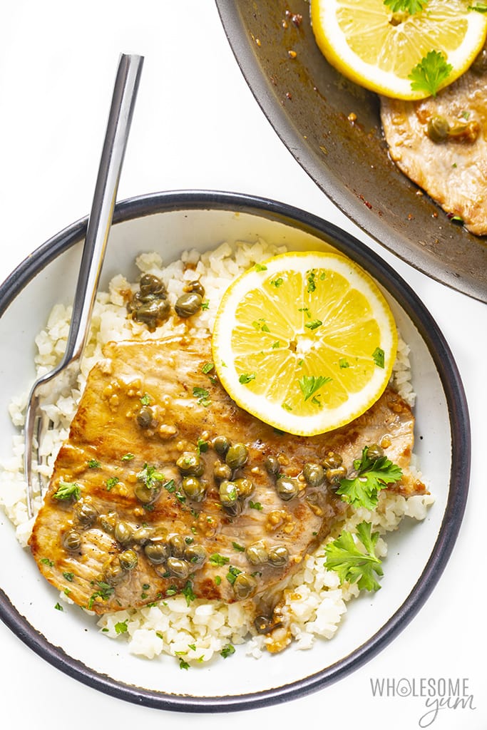 Overhead view of veal scallopini garnished with a lemon slice