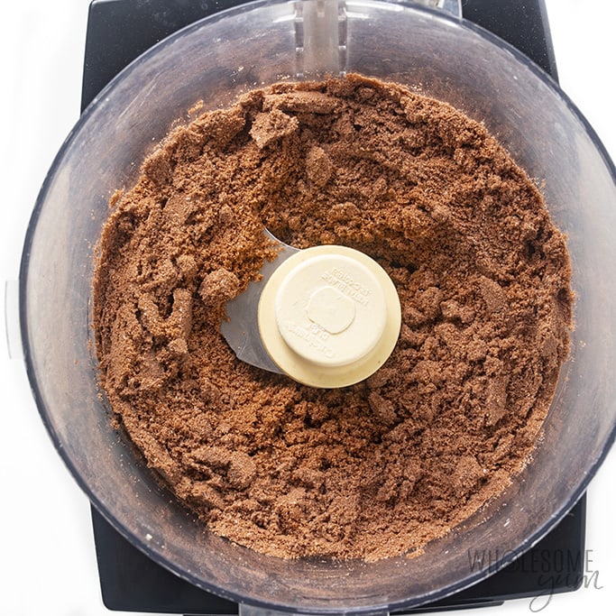 Overhead view of a food processor with ingredients for the crust of the peanut butter cup cheesecake
