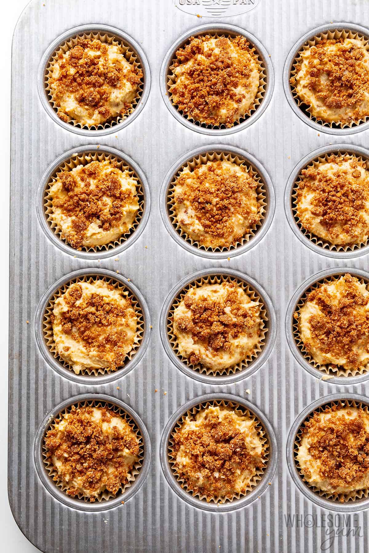 Coffee cake muffins assembled and topped with streusel before baking.