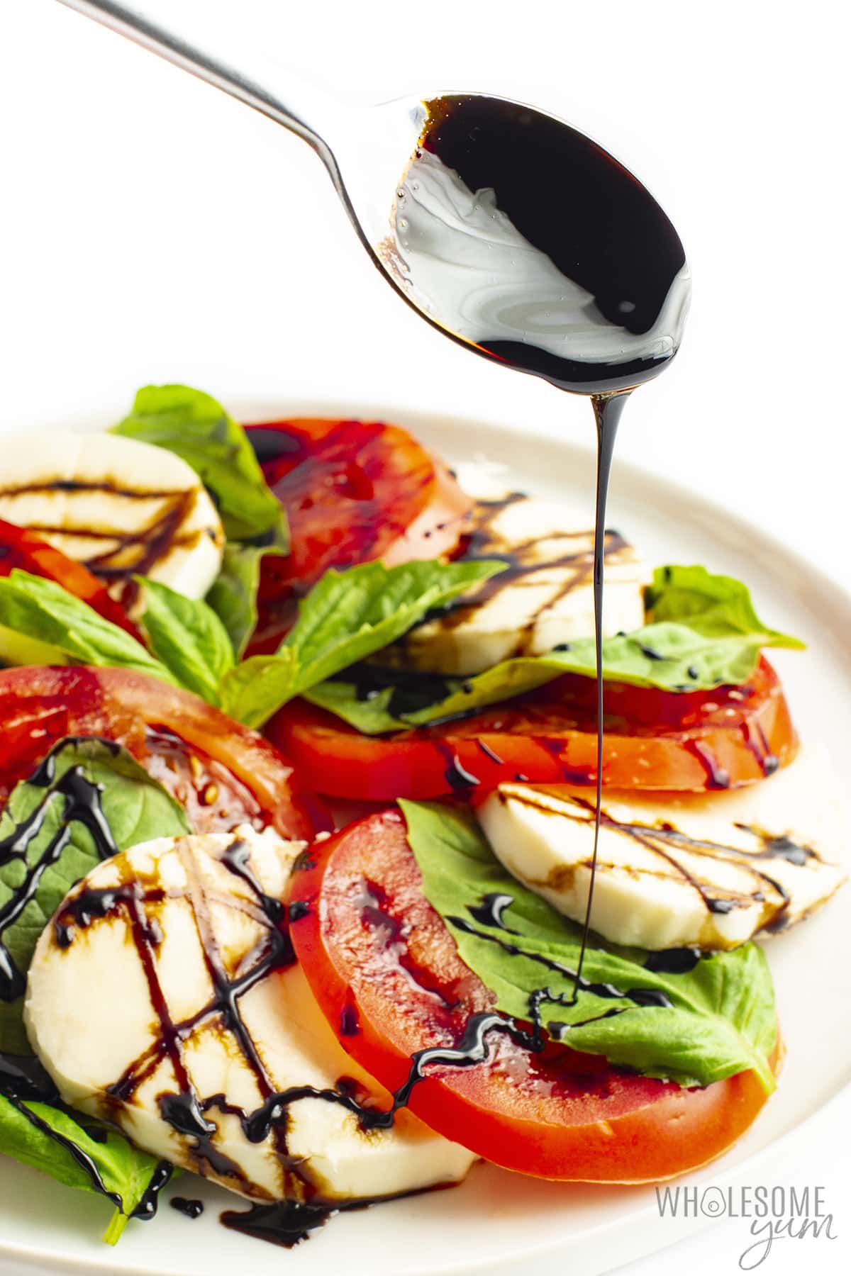 Caprese salad with balsamic glaze being drizzled on top.