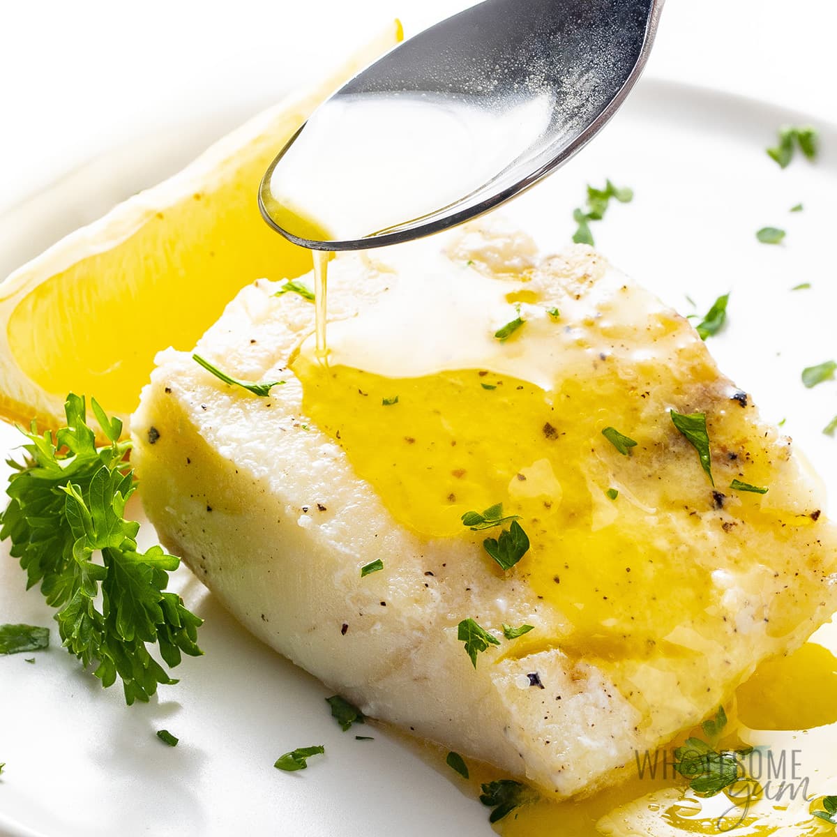 Lemon butter sauce drizzled over fish with a spoon.