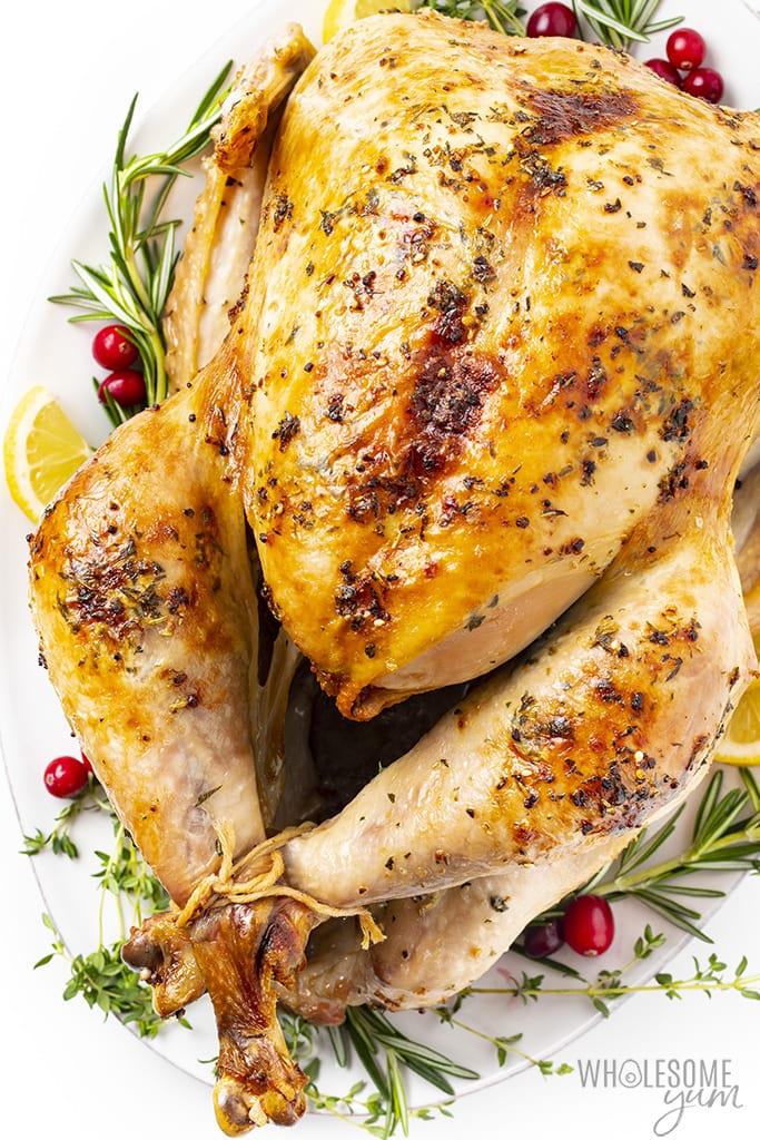 Roasted keto turkey on a platter with cranberries and rosemary