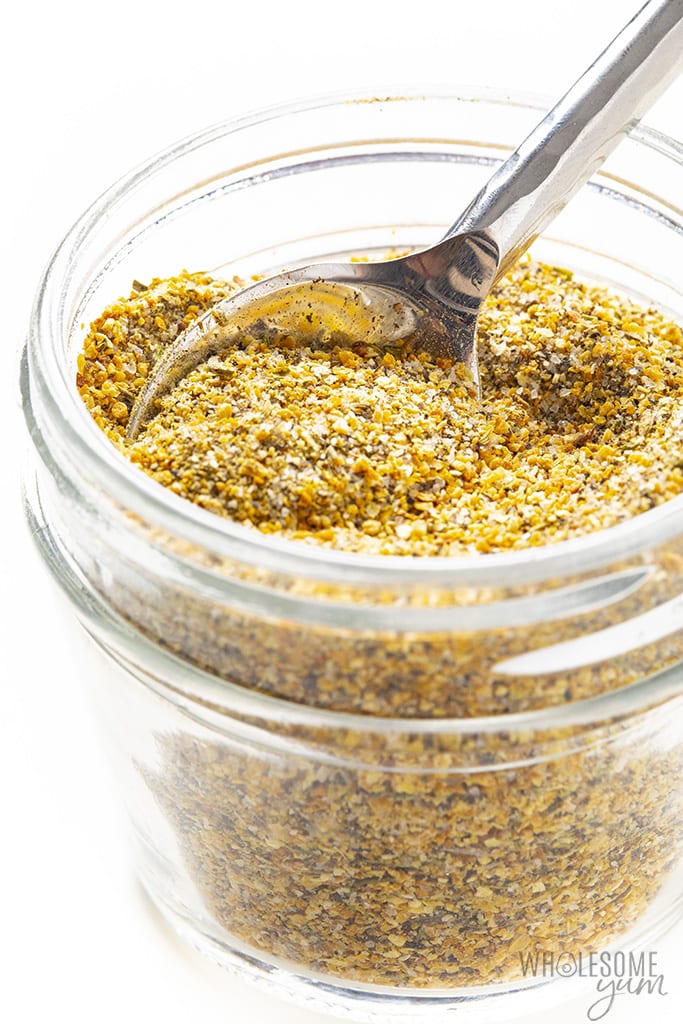 Homemade lemon pepper seasoning in a glass jar with a spoon