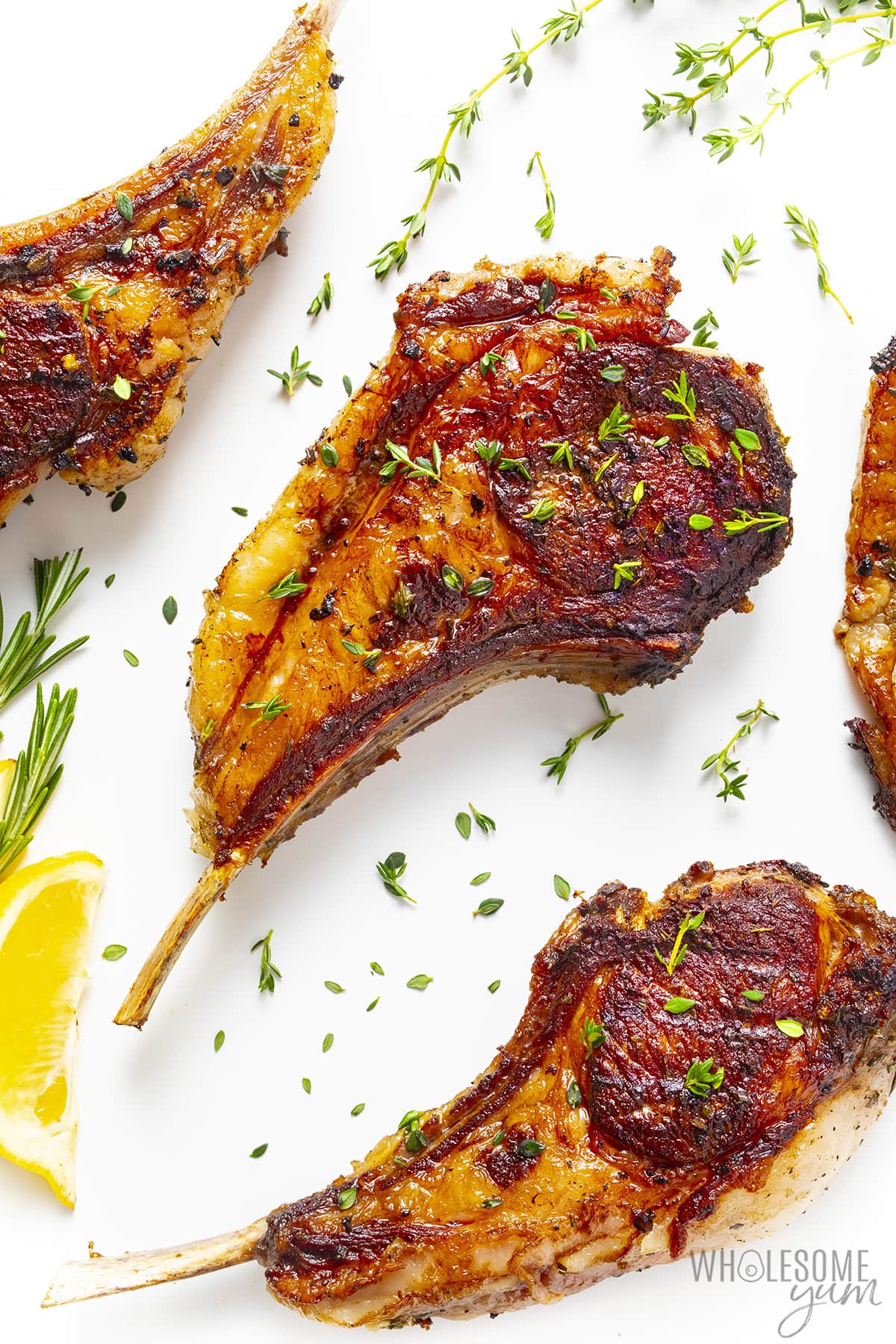 Oven baked lamb chops on a white surface.