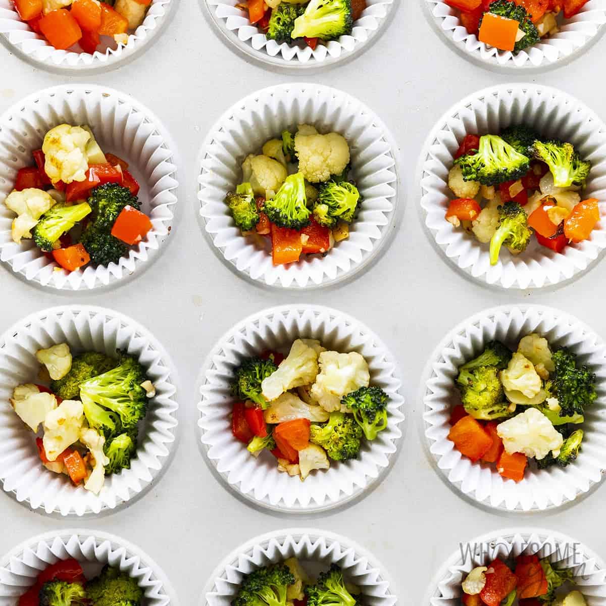 Muffin tin filled with roasted vegetables.