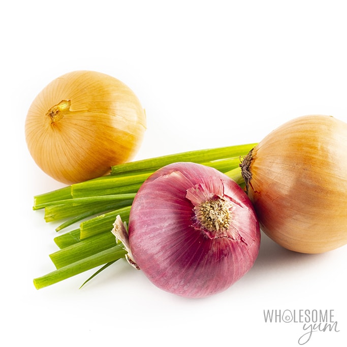 Two yellow onions, one red onion, and a bundle of green onions