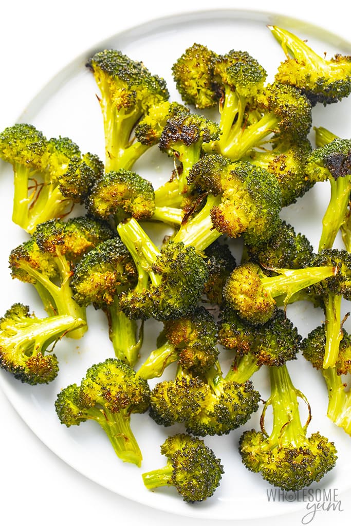 Pile of roasted broccoli on a white plate.
