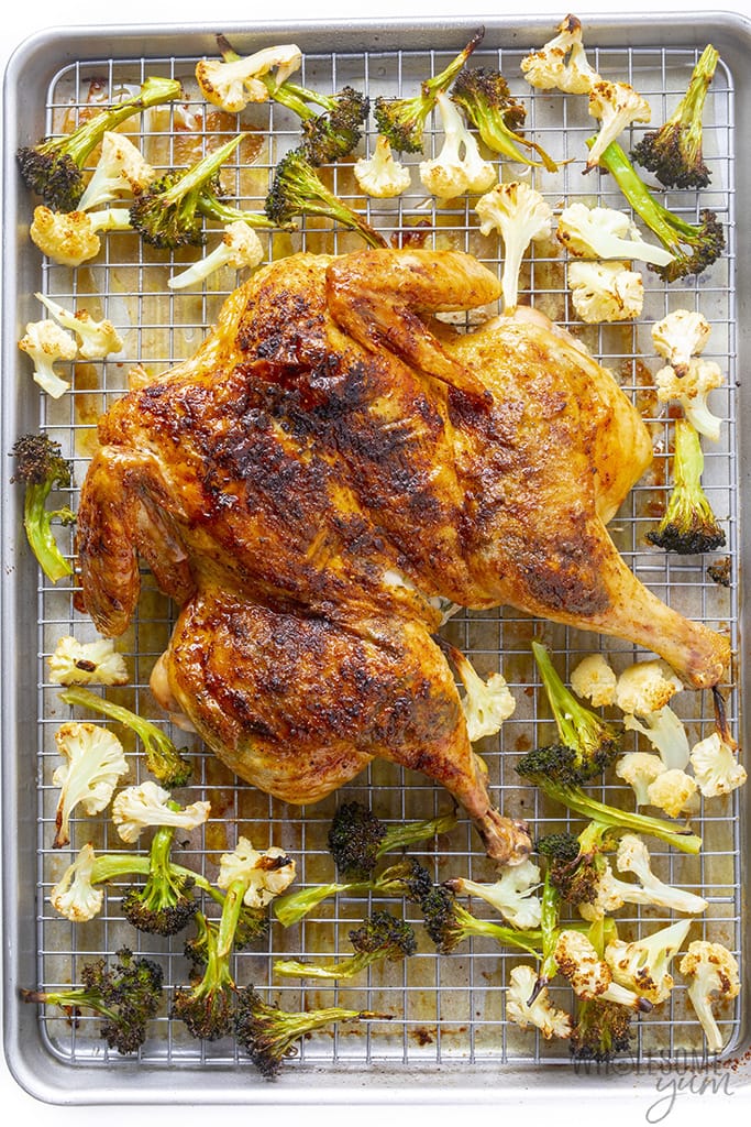 Spatchcock roast chicken on a baking sheet with vegetables