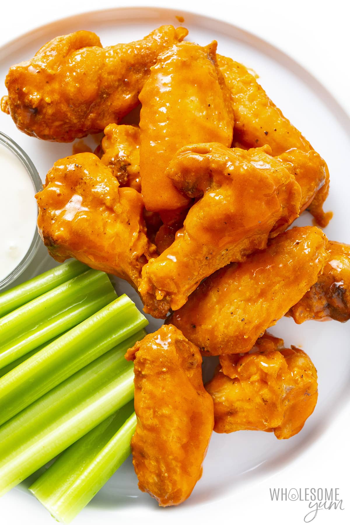 Buffalo chicken wings recipe on a plate with blue cheese and celery.