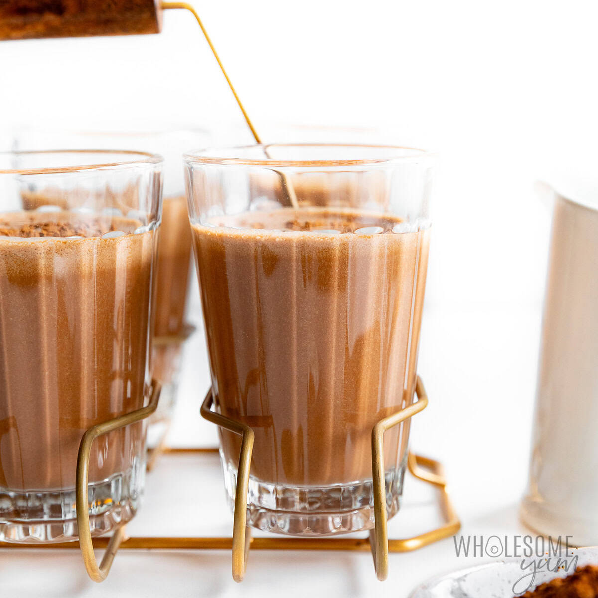 Creamy sugar free chocolate milk in glasses sprinkled with cocoa powder.