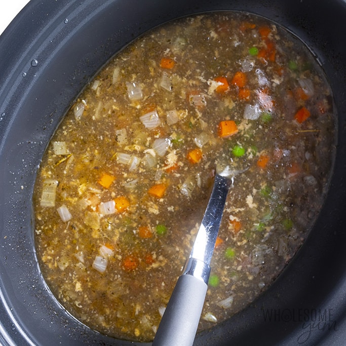 Crock pot with peas and carrots for pot pie soup cooking