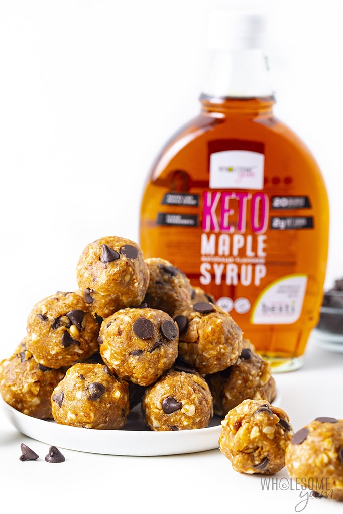 White plate with stack of low carb energy balls and a bottle of keto maple syrup