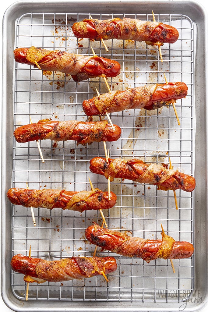Bacon wrapped hot dogs baked on a pan