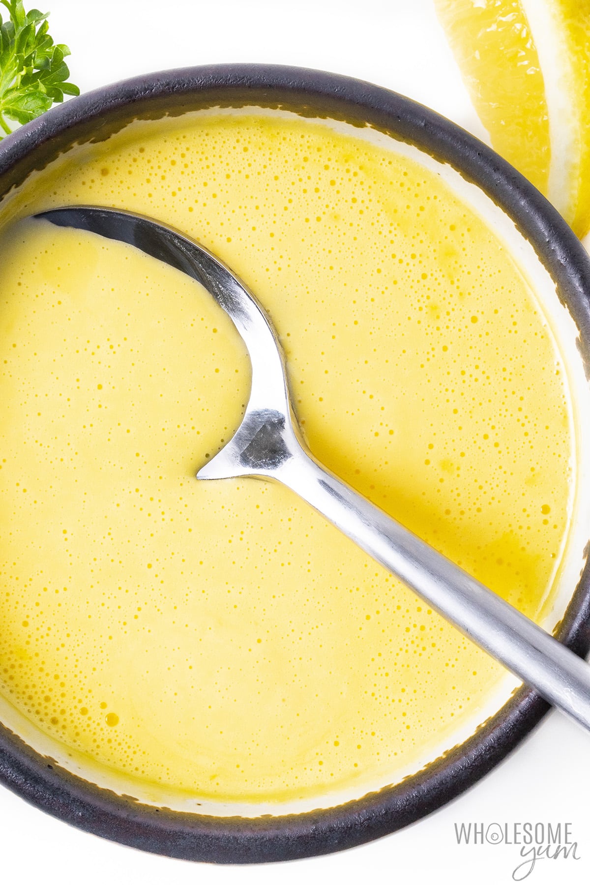 Blender hollandaise in a bowl with a spoon.
