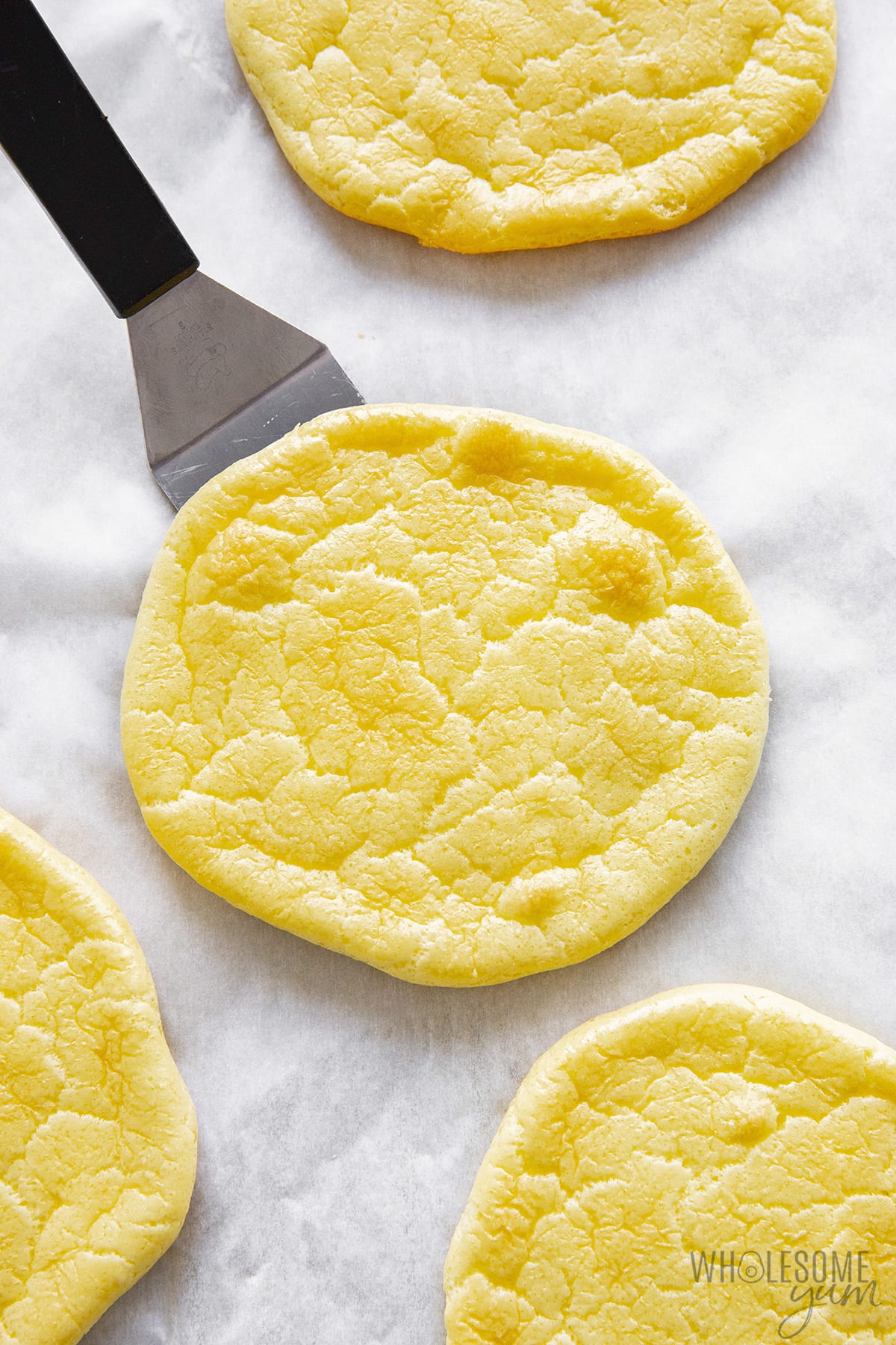 Baked cloud bread on baking sheet with spatula.