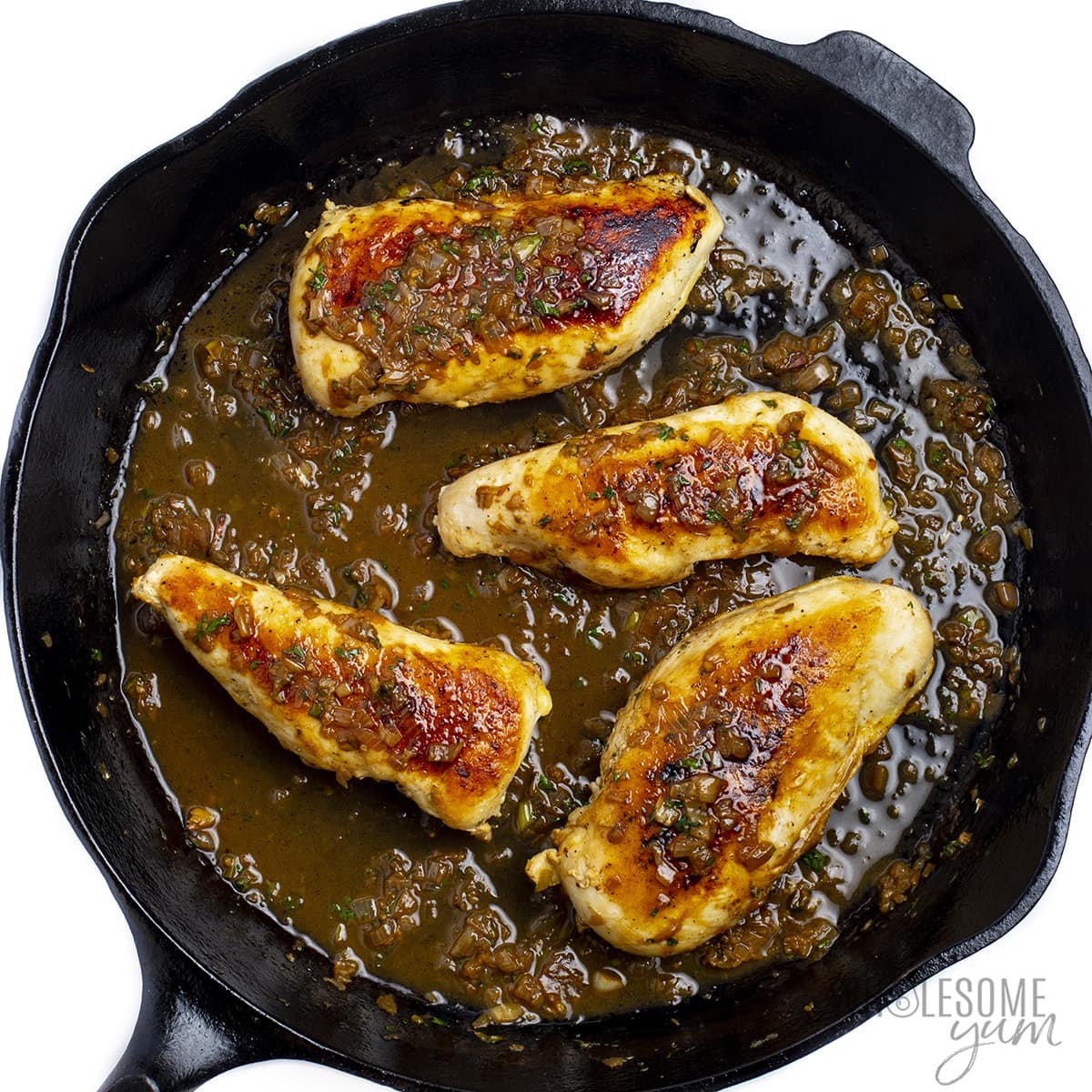 Pan seared chicken breasts added back to the skillet and drizzled with sauce.