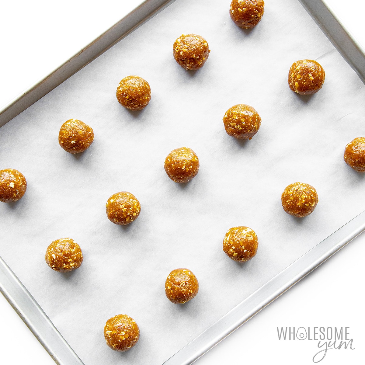 Balls of cookie dough on a prepared baking sheet.