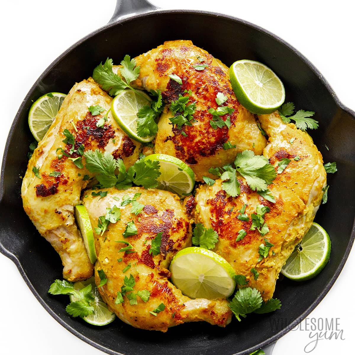 Baked tandoori chicken and limes in cast iron skillet.