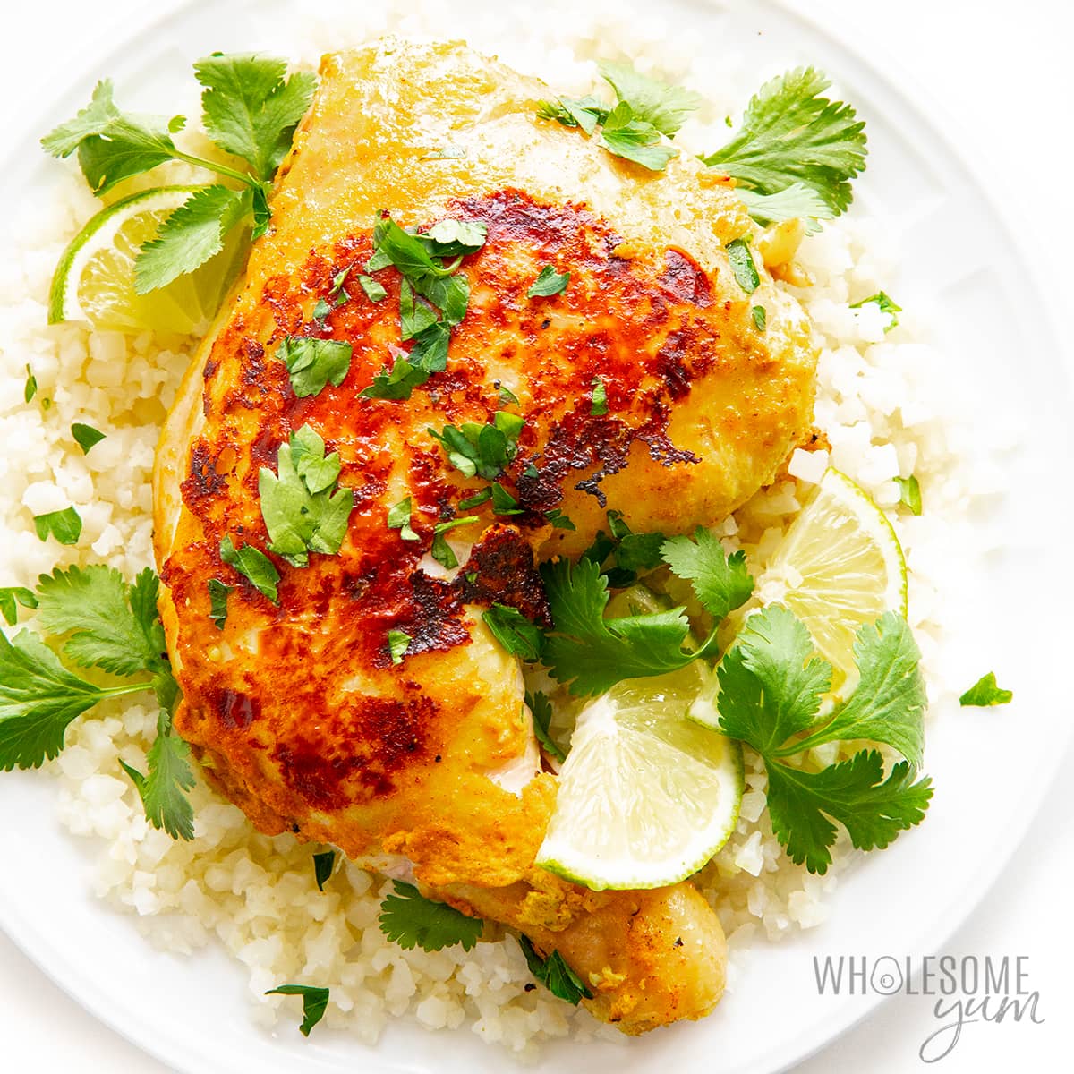 Baked tandoori chicken recipe on a plate with cilantro and lime