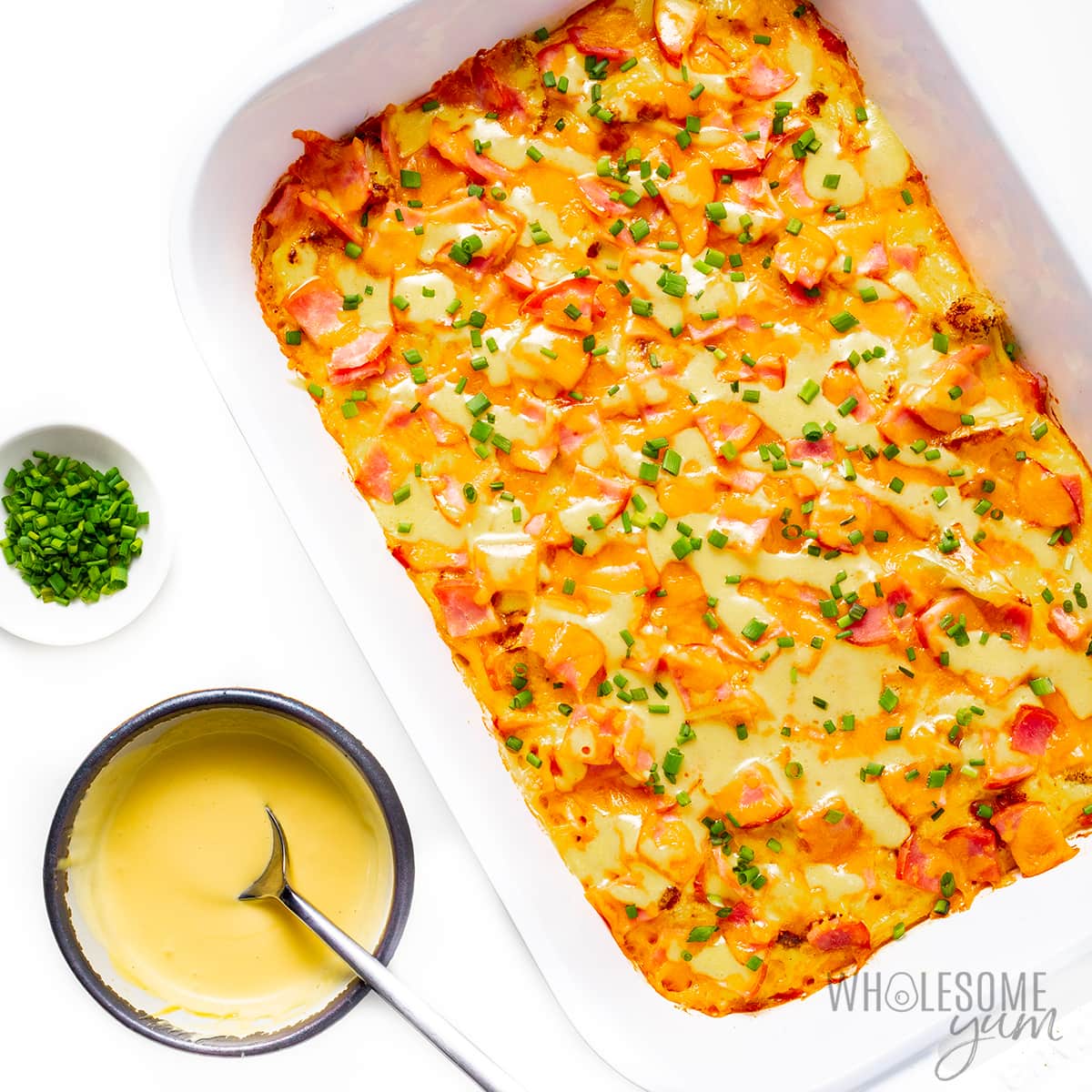Eggs benedict casserole recipe in a baking dish with hollandaise sauce