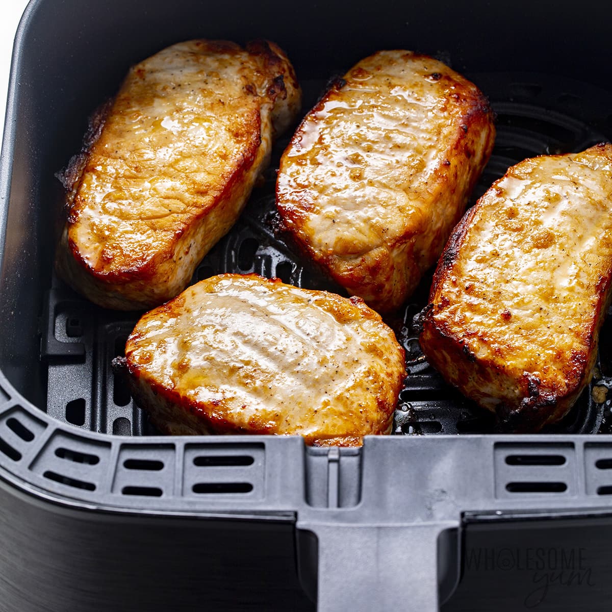 Cooked pork chops in air fryer basket.