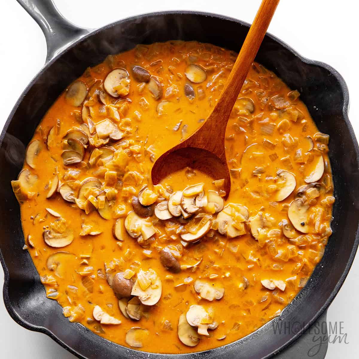 Stirring the creamy mushroom gravy with a wooden spoon.