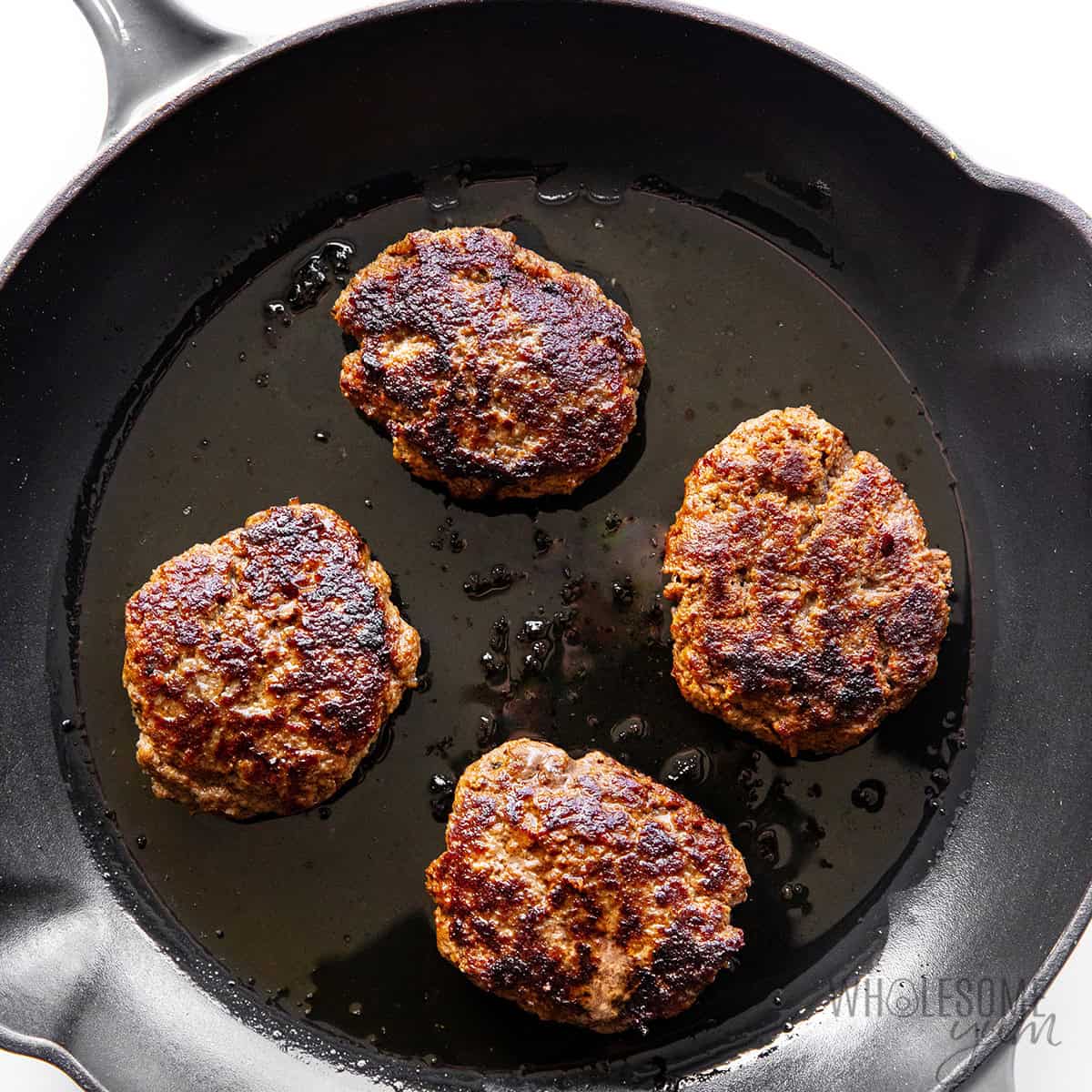 Searing the hamburger patties in a large skillet.