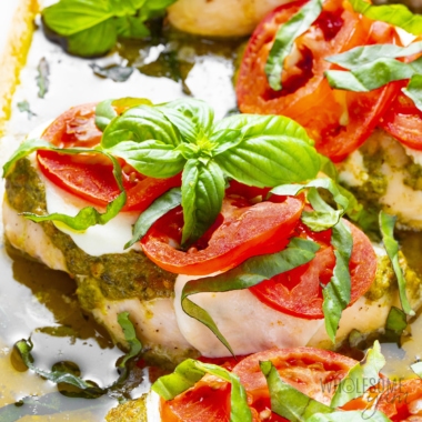 Pesto chicken close up, topped with fresh basil ribbons and a cluster of basil.