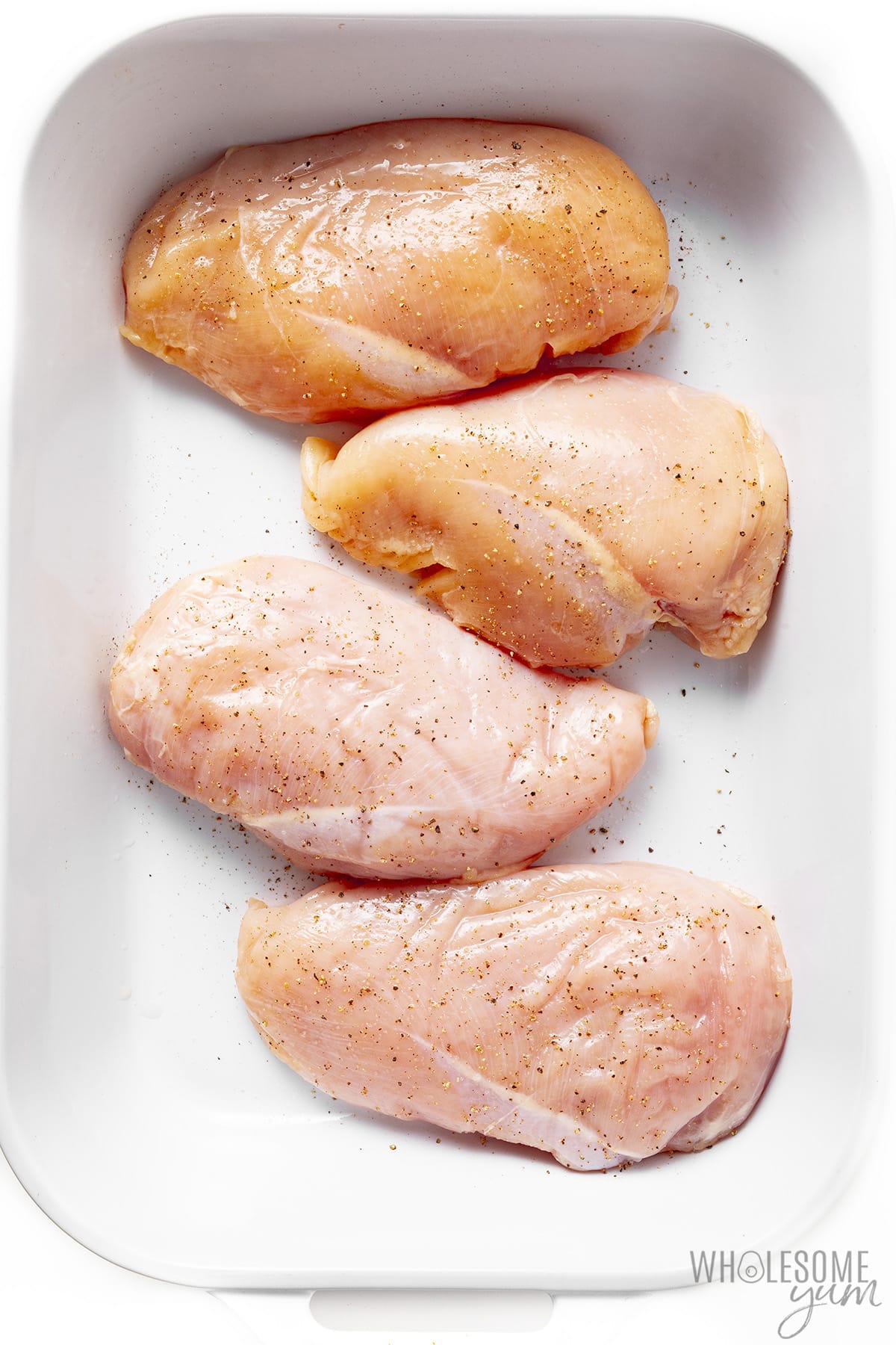 Seasoned chicken breasts arranged in a baking dish.
