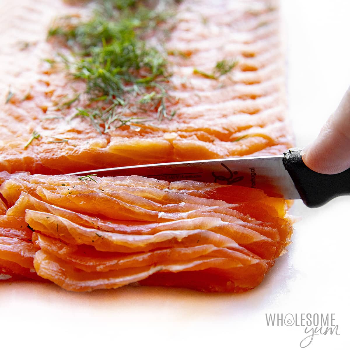 Slicing lox salmon thinly with a knife.