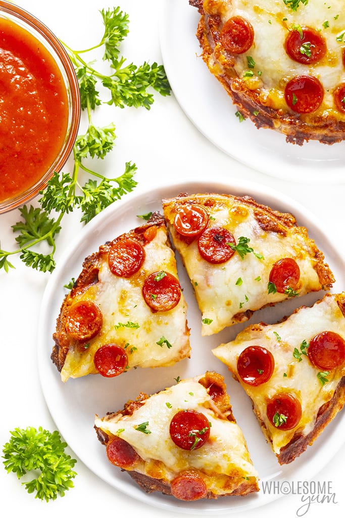 Sliced chaffle pizza recipe on plates next to a bowl of pizza sauce