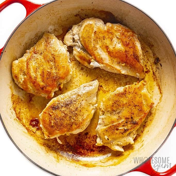 Seasoned chicken breast cooking in a cast iron skillet
