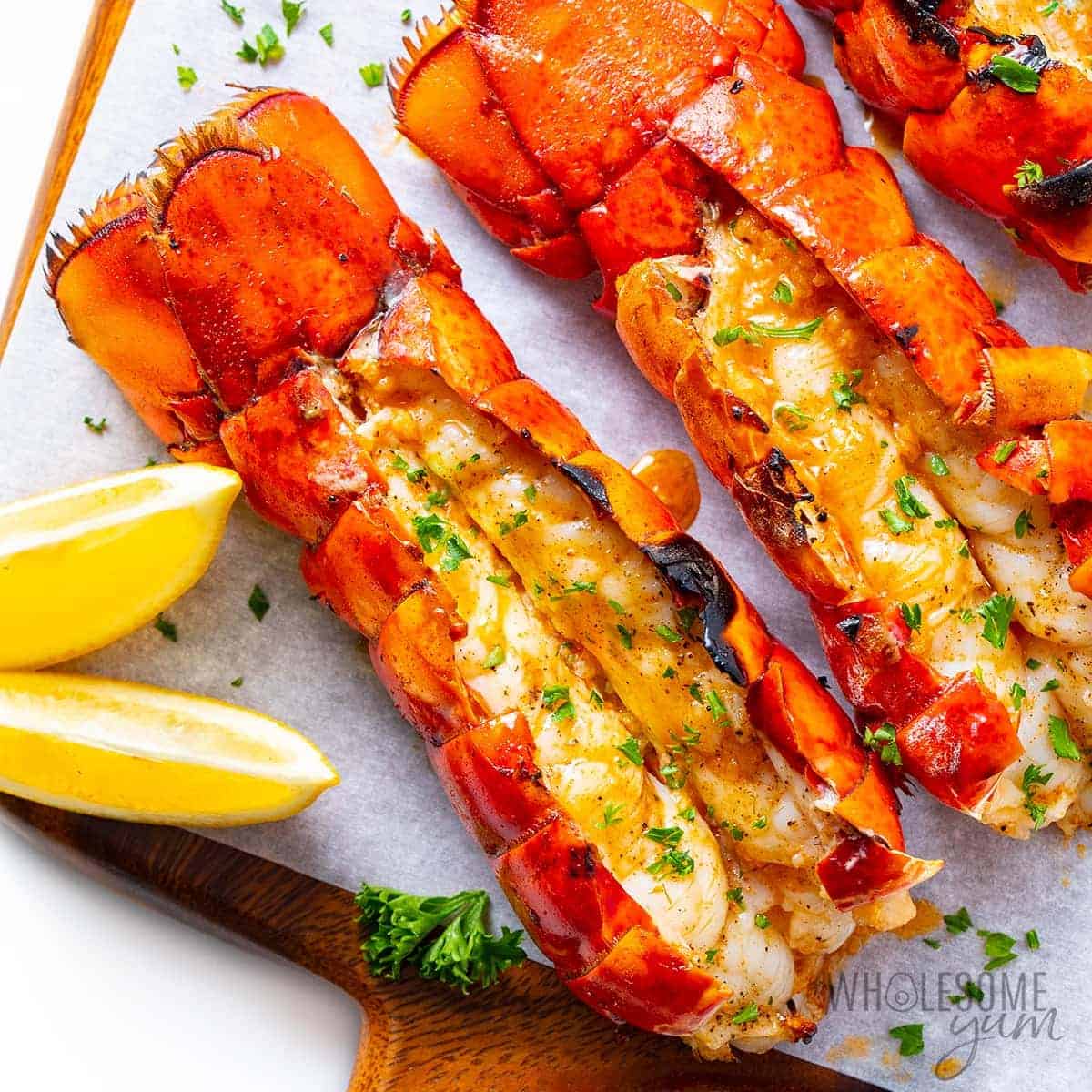 Grilled lobster tail on a cutting board.