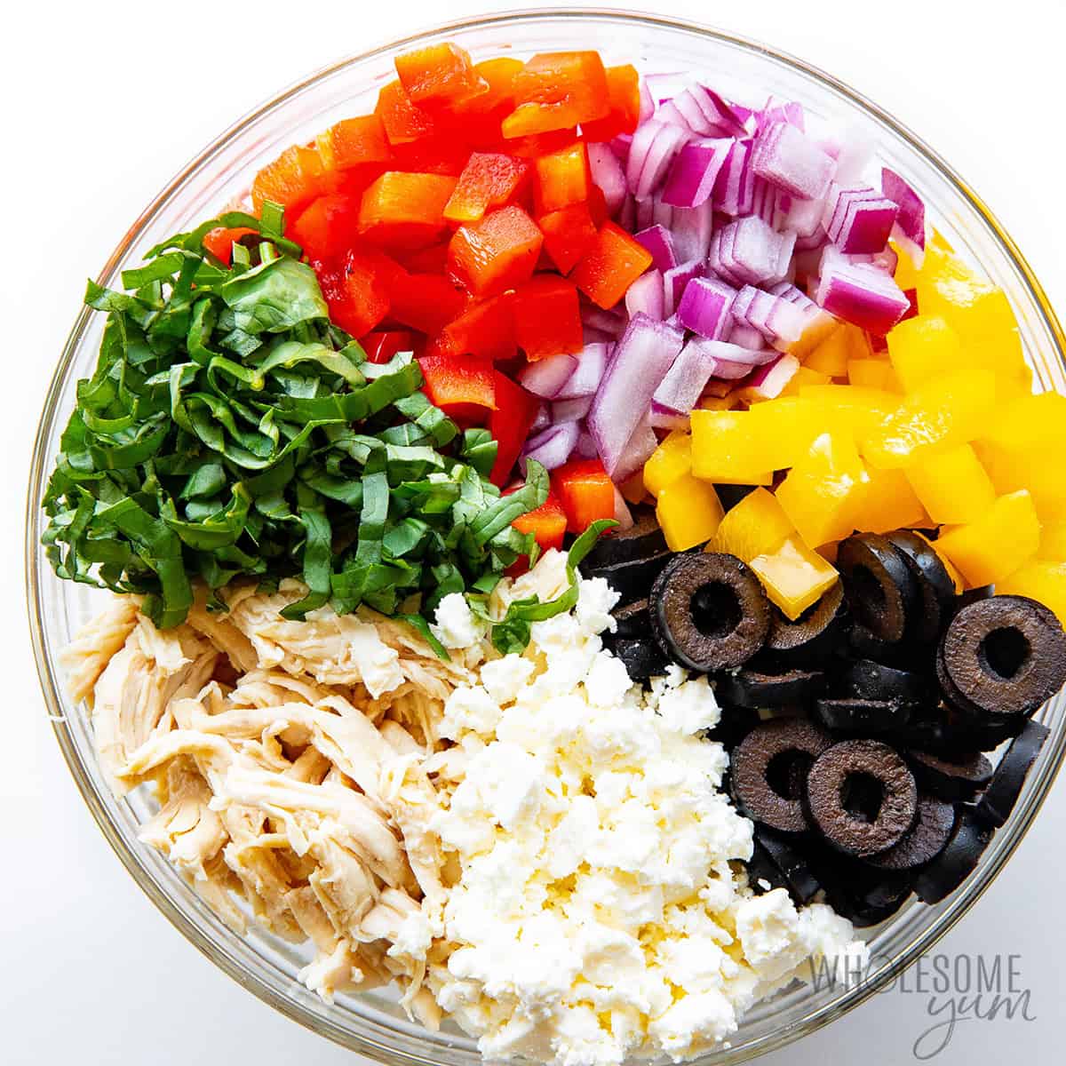 Chicken, veggies, herbs, and cheese combined in a large bowl.