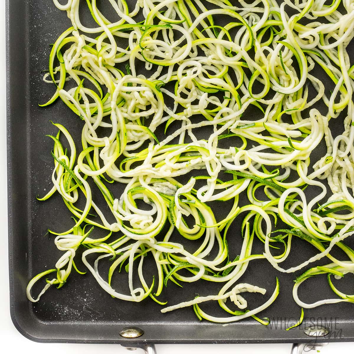 Cooked zucchini noodles on a baking sheet.