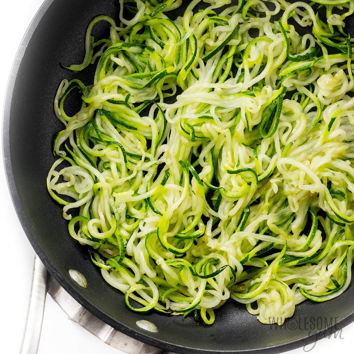 Cooked zucchini noodles in a skillet.