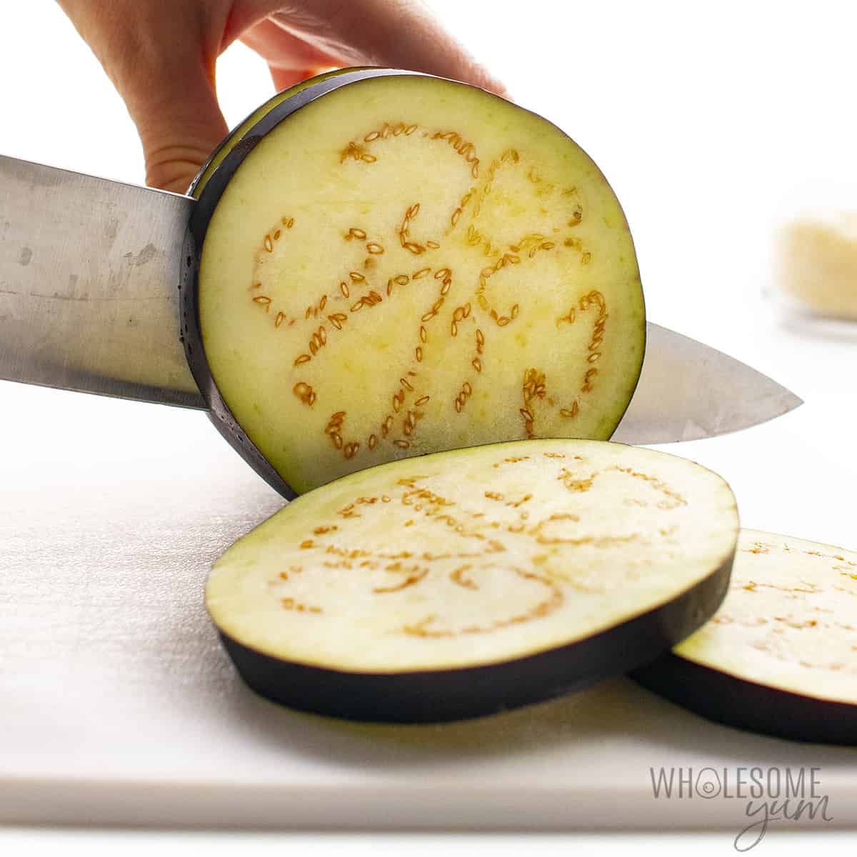 Knife cutting slices of eggplant