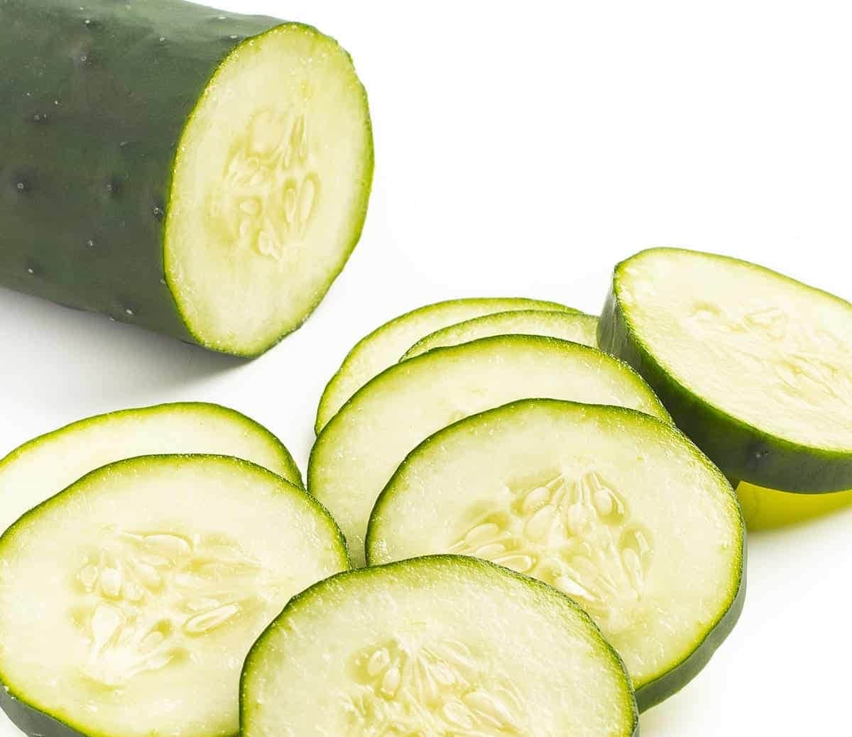 Cucumber cut into slices on white background.