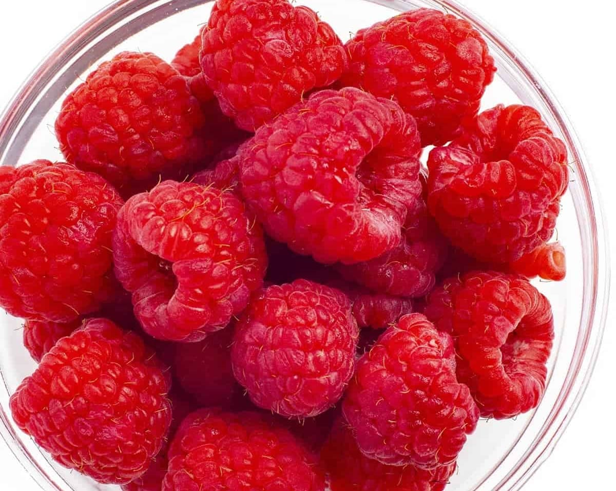 Raspberries in a bowl on white background.
